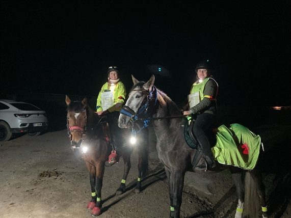 Cavaliers en balade de nuit, équipés de gilets et de lampes réfléchissants.