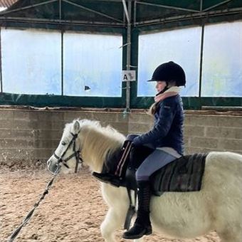Enfant debout en équilibre sur son poney pendant un exercice de voltige.